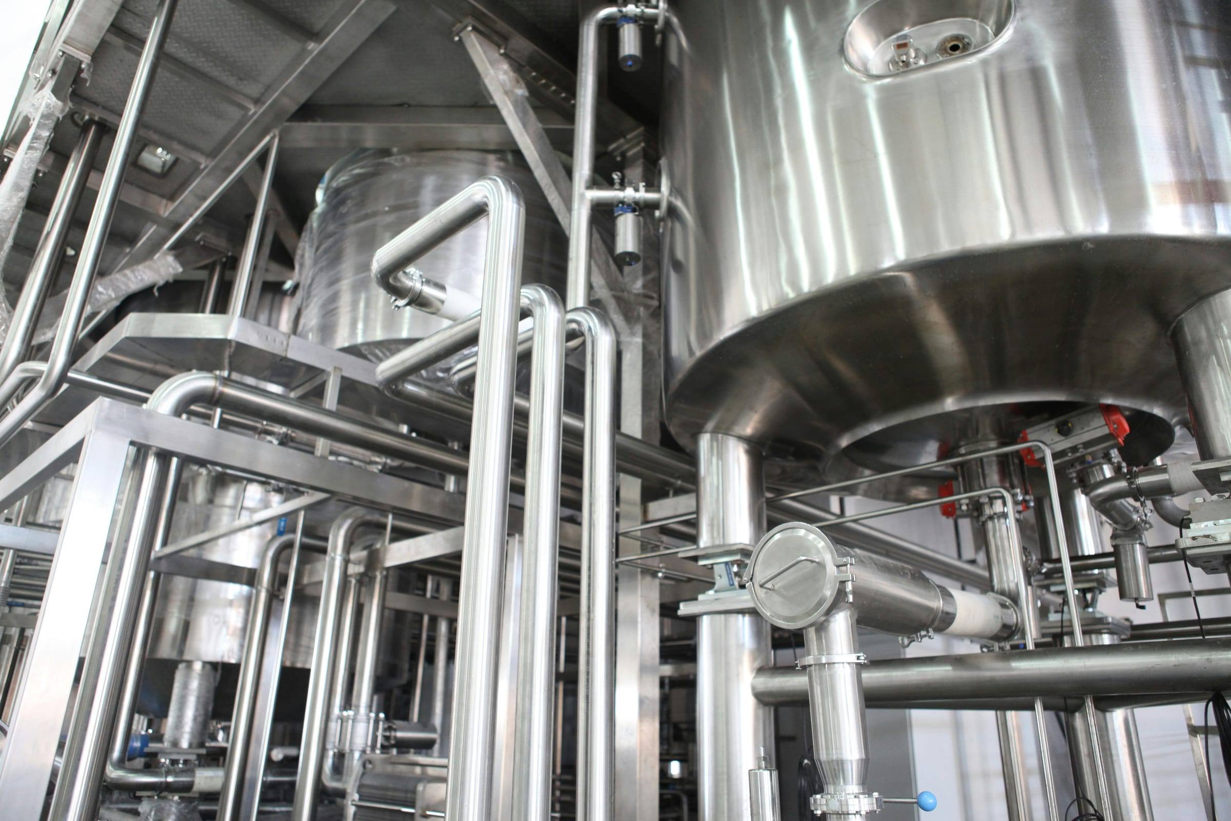 Stainless steel processing tanks and sanitary piping in an industrial plant.